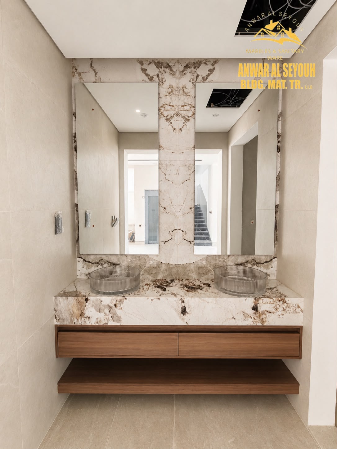 Twin vanity in book-matched marble with two fluted glass basins, a wooden drawer unit and open shelf