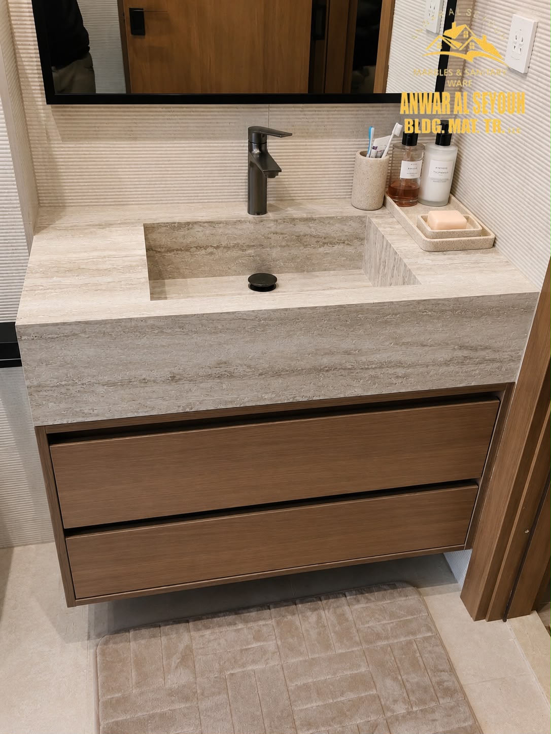 Close view of a travertine counter with the basin cut into the stone and two handleless wooden drawers below